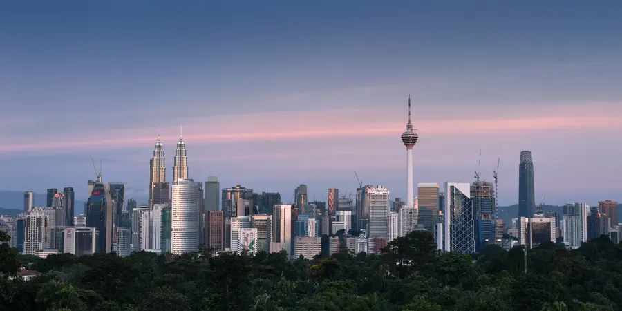 The Kuala Lumpur skyline at dusk, seen across the trees